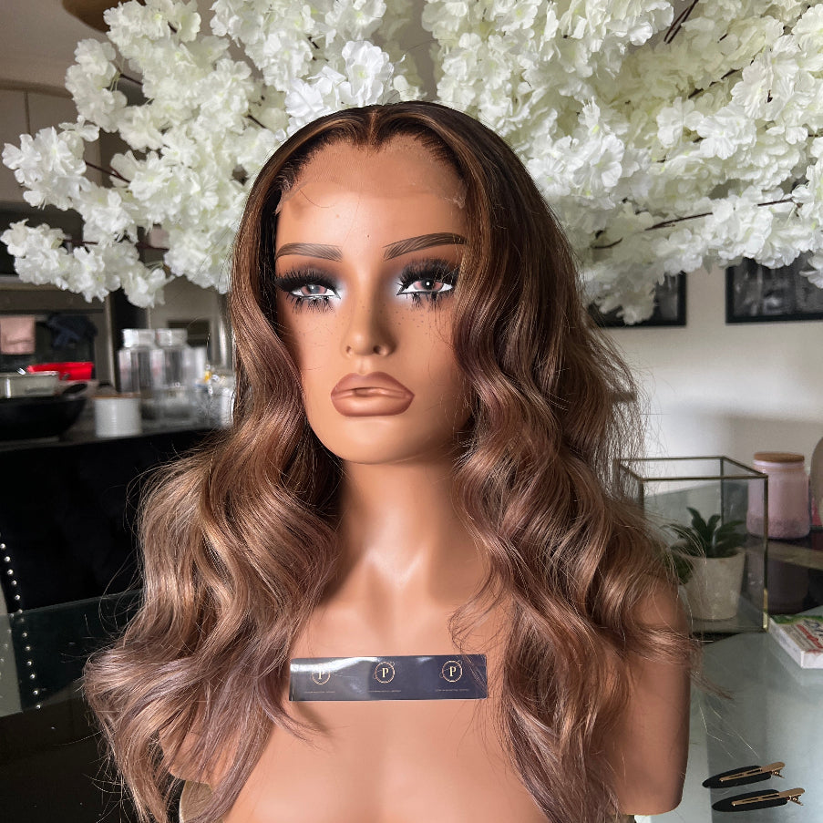 Mannequin head with long wavy hair against a white floral background